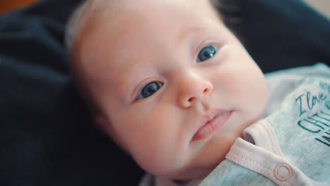 a beautiful blue-eyed newborn baby lying on a black background and looking at the camera