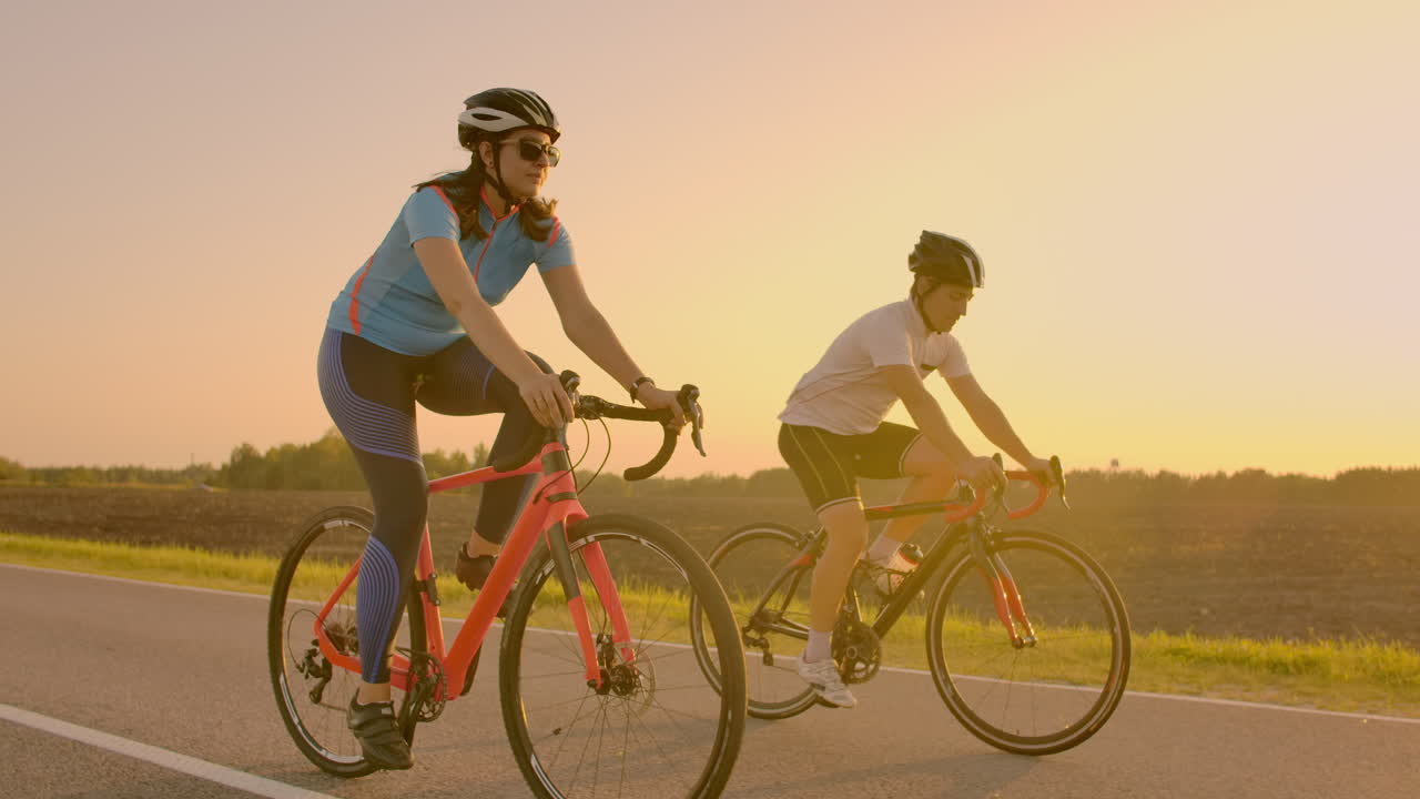 espacio vacío. amigos deportivos en bicicleta al atardecer. pareja de ciclistas van a lo largo de la costa. deporte en el fondo de la naturaleza. grupo de personas dos ciclistas de carretera al atarrear el sol.