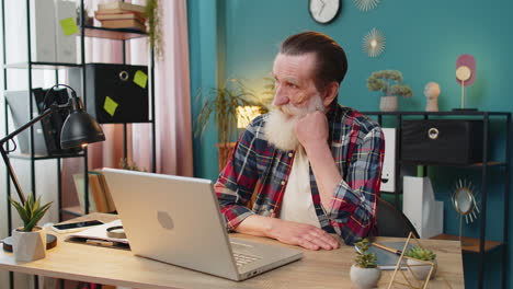 thoughtful senior man looking away thinking solving problem with laptop make decision lack of ideas