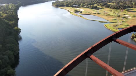 Aerial-drone-shot-of-Pennyback-bridge-with-cars-passing-by-in-Austin,-Texas,-USA-over-Lake-Austin-at-daytime