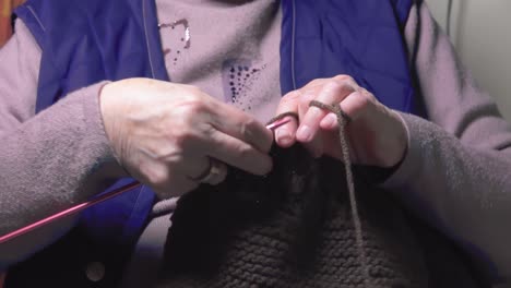 senior mature lady elder grandma female hands doing handicraft handwork hobby concept sitting on couch at home, close up view