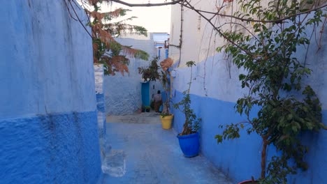 Moroccan-woman-walks-down-Chefchaouen-Medina-Blue-alley,-Morocco