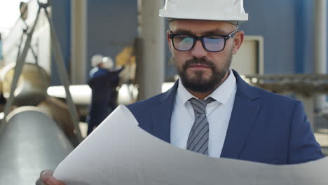 engineer studying blueprint in industrial workplace