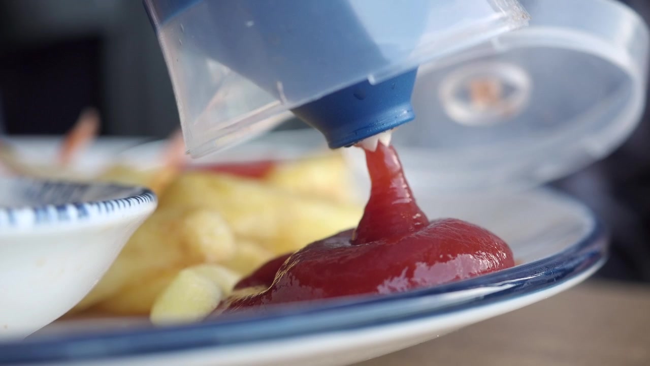 Spremere ketchup rosso su un piatto di patatine fritte