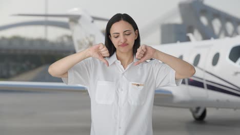 una mujer piloto india decepcionada mostrando los pulgares hacia abajo
