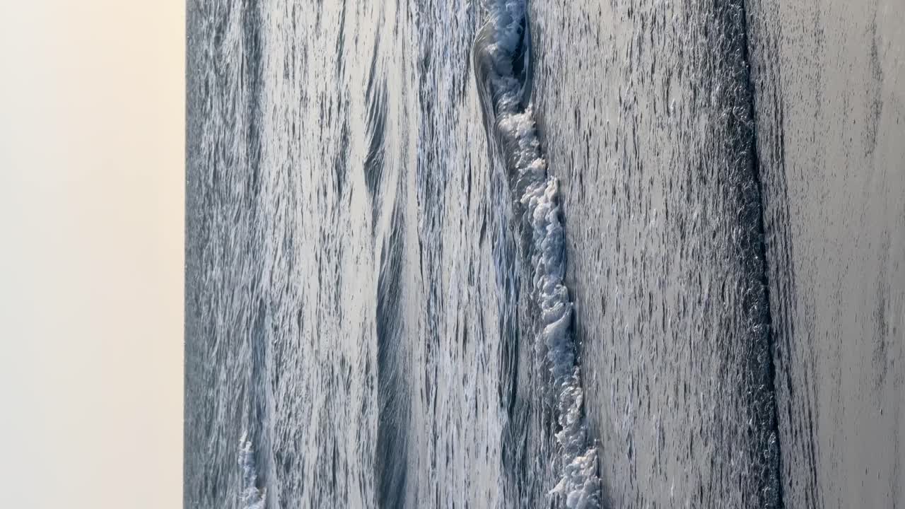 Vertical video of small sea waves on the coast