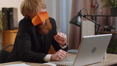 tired inefficient lazy business man working sleeping on laptop computer with eyes stickers on face