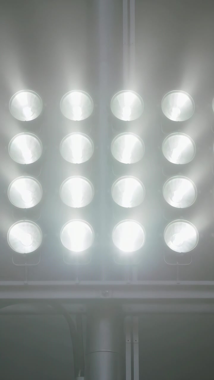 Vertical video: Filming camera showing LED grid glare shifts and jitter at office ceiling, conduit
