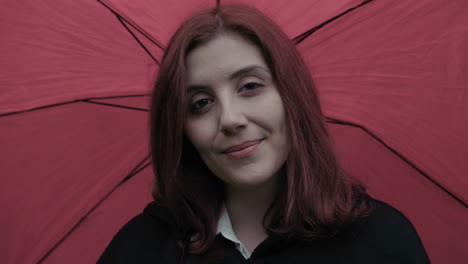 joven italiana sonriendo cabello rojo y paraguas durante la lluvia al aire libre