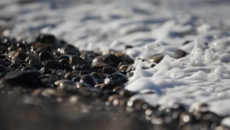 ocean waves on pebbles beach, foamy ocean water, closeup