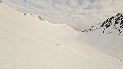 Inmensidad-De-Montañas-Nevadas-En-Comparación-Con-Un-Pequeño-Grupo-De-Personas,-Vista-Aérea