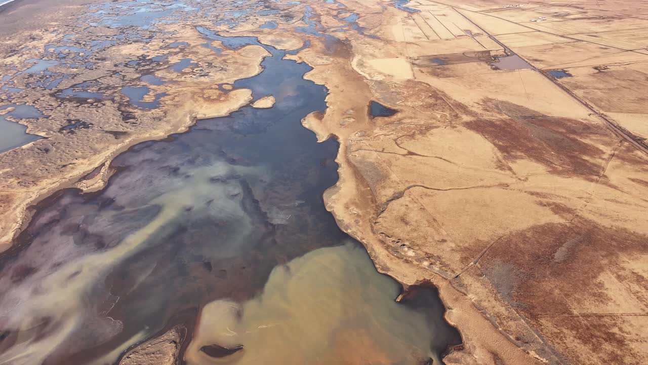 Aerial view of the Þjórsá River delta in Iceland, where winding waterways and wetlands meet the coastline, creating a vast and intricate natural mosaic.
