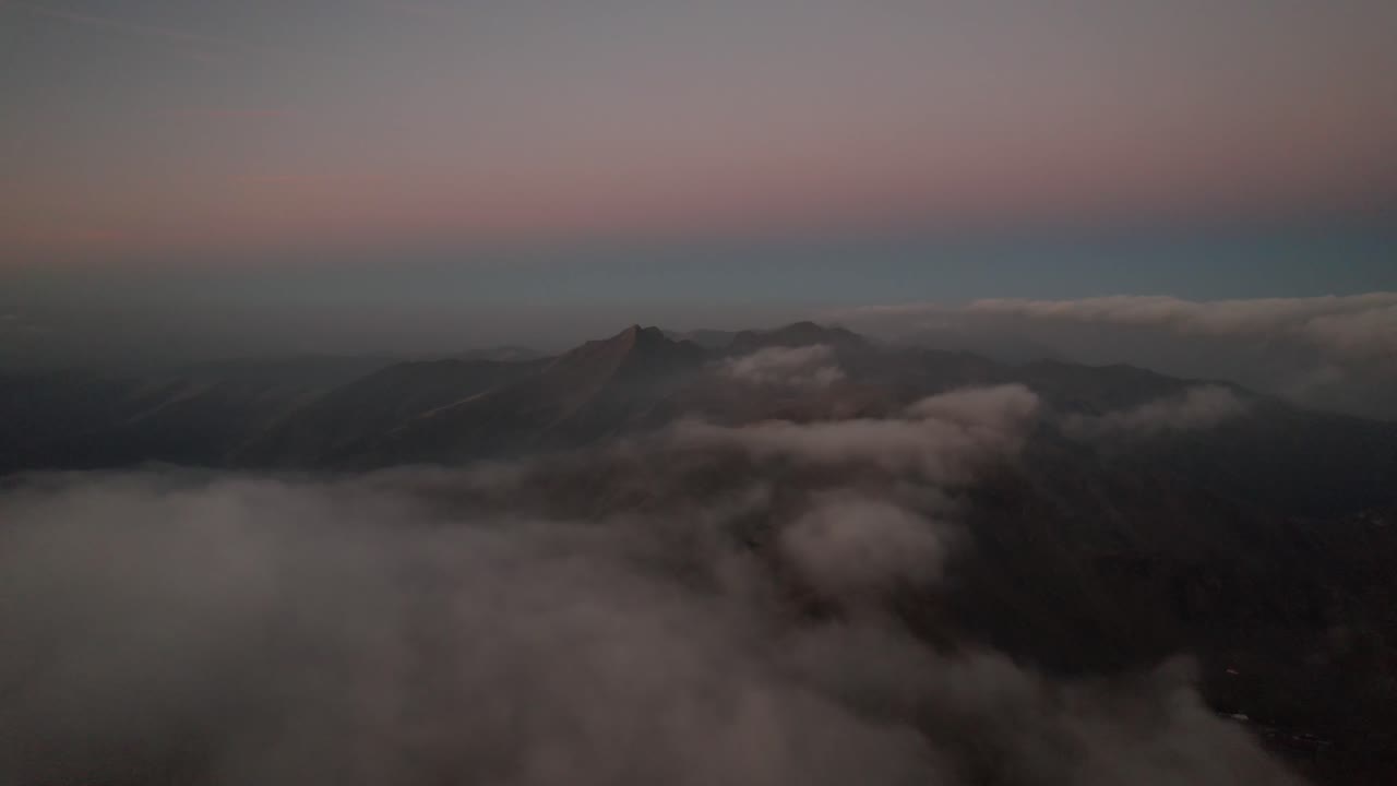 Majestic mountain peaks above soft clouds at sunrise, evoking calm and awe