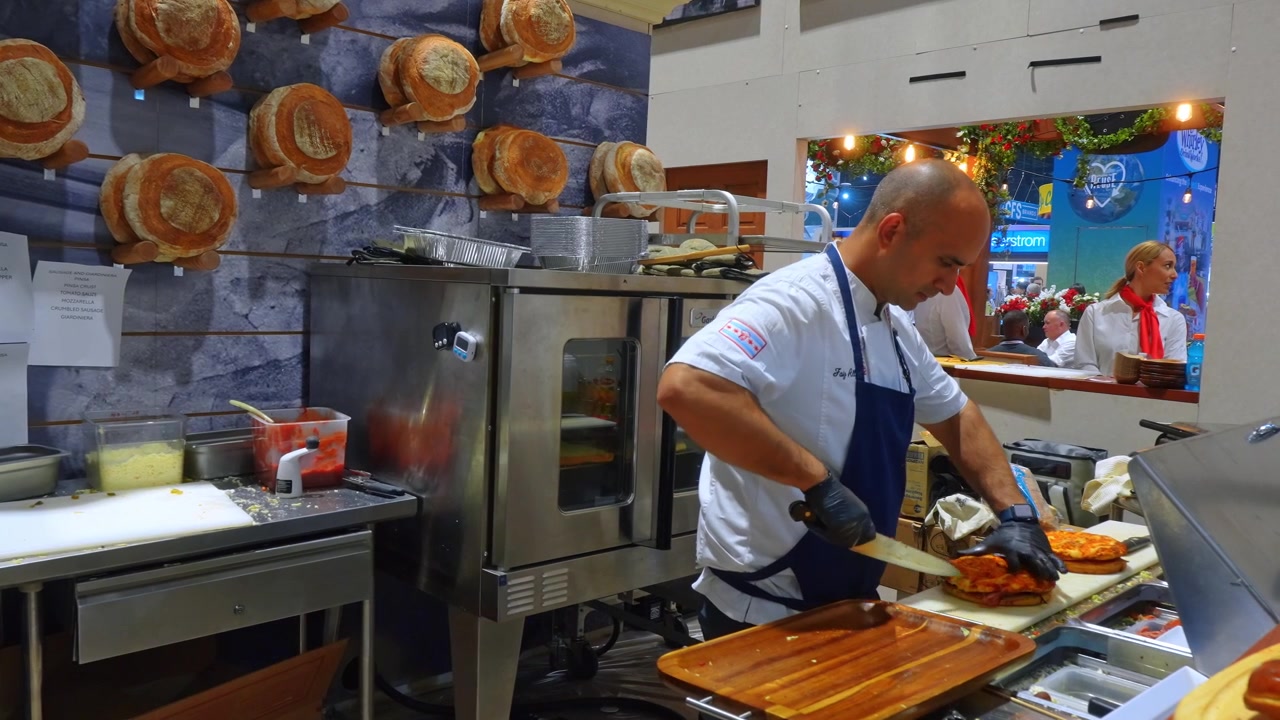 Chicago, USA, 7 maggio 2026: Cucina professionale di panetteria con personale e forno. Un fornaio sta vicino a un forno commerciale in acciaio inossidabile mentre le lavoratrici conversano dietro un bancone di servizio