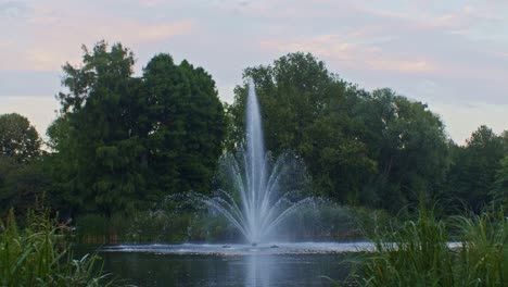 a nice and beautiful running water fountain on a pond in the amsterdam's city town park in the evening in netherlands europe