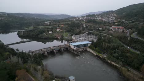 Angled-push-in-drone-to-flowing-water-from-Velle-water-dam-and-power-plant-in-Ourense,-Galicia,-Spain