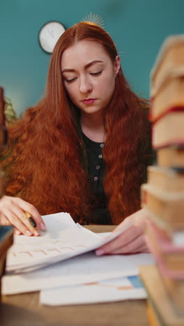 Exhausted-business-woman-looking-at-documents-reports-stacks-of-books-while-working-hard-at-office