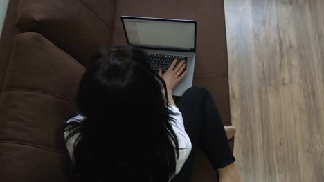 소파에 앉아 있는 집에서 노트북을 사용하는 젊은 여성
