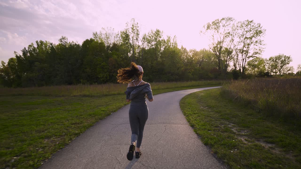 seguindo uma jovem latina atlética correndo por uma trilha em um parque exuberante
