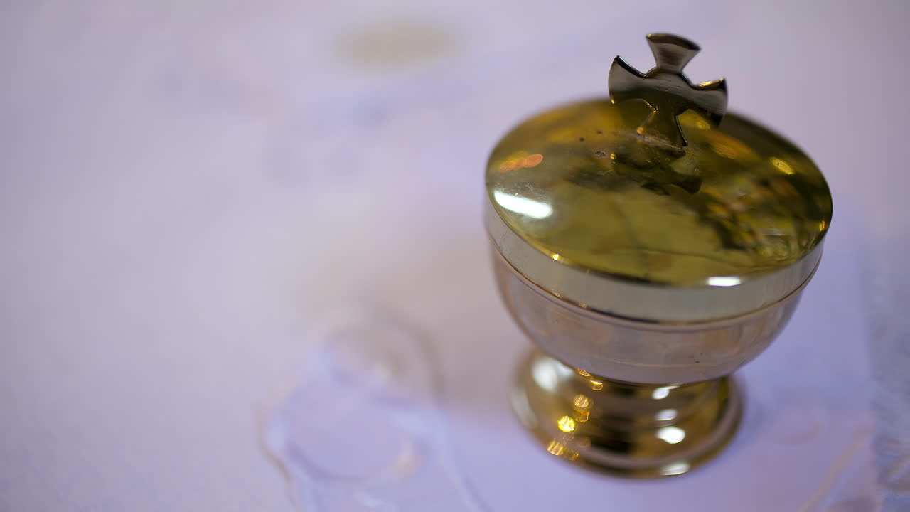 Copón dorado con cruz sobre un mantel de altar blanco