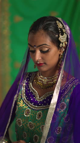 vertical video close up portrait of female kathak dancer performing dance wearing traditional indian dress and jewellery looking at camera 3