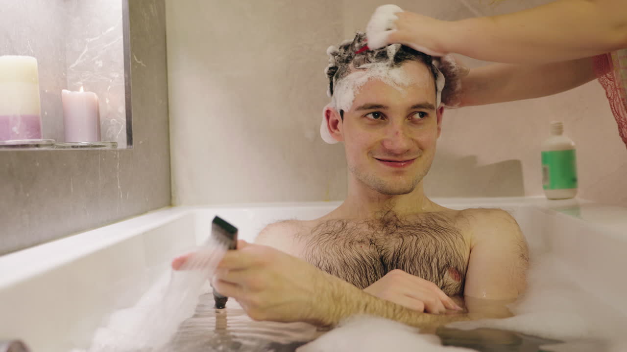 Uomo che si fa lo shampoo nella vasca da bagno