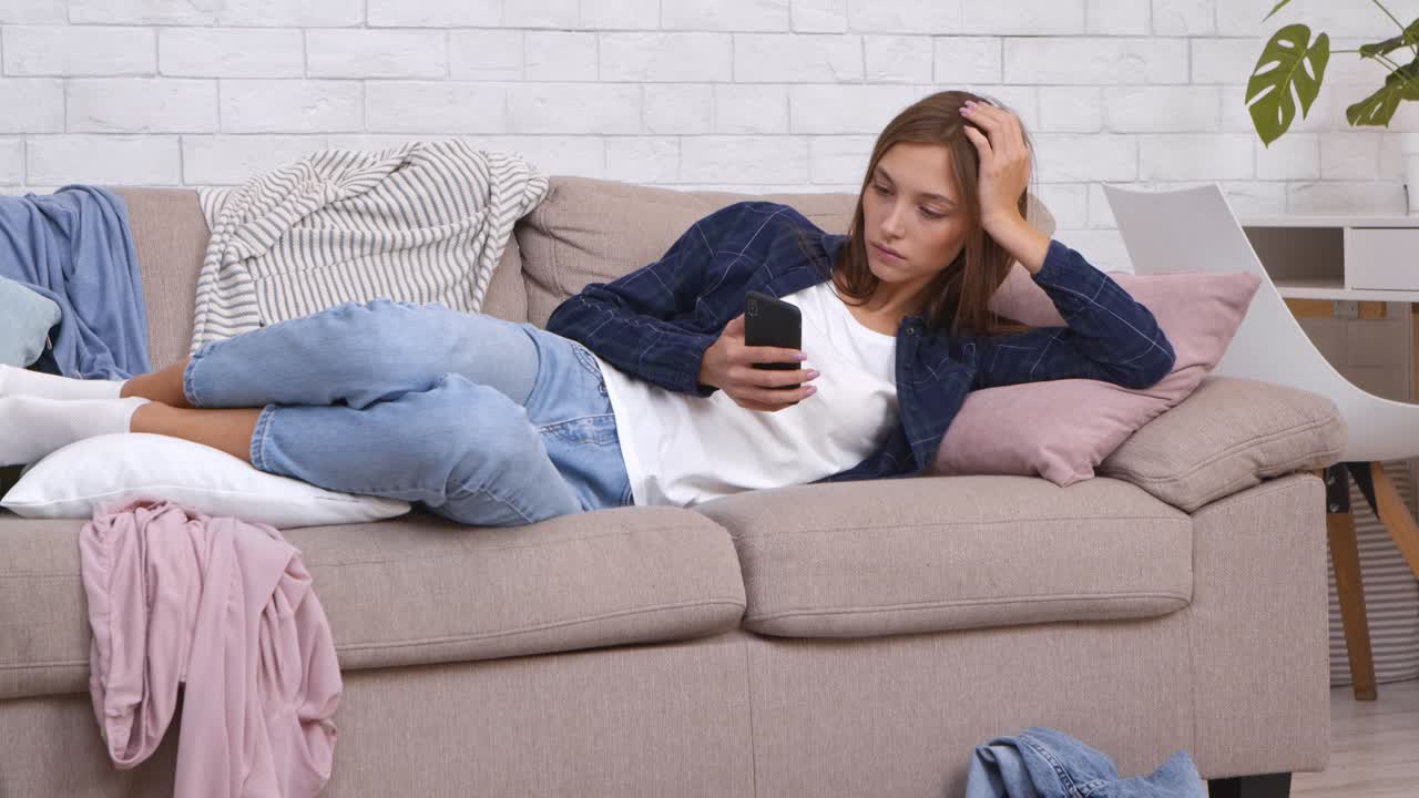 una adolescente relajándose en el sofá y usando el teléfono.