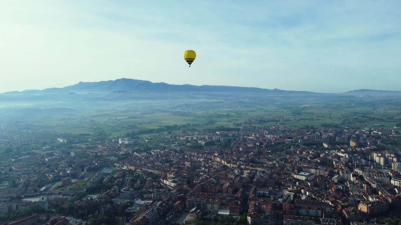 Hot Air Balloon Over Cityscape with Mountains and Valley