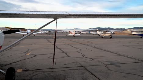 Cessna-182-airplane-wing-at-Colorado-metro-airport-with-planes-on-paddock,-pan