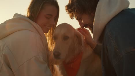 close-up shot: a guy and a girl are petting their dog on a sunny beach in the morning. happy walk with pet