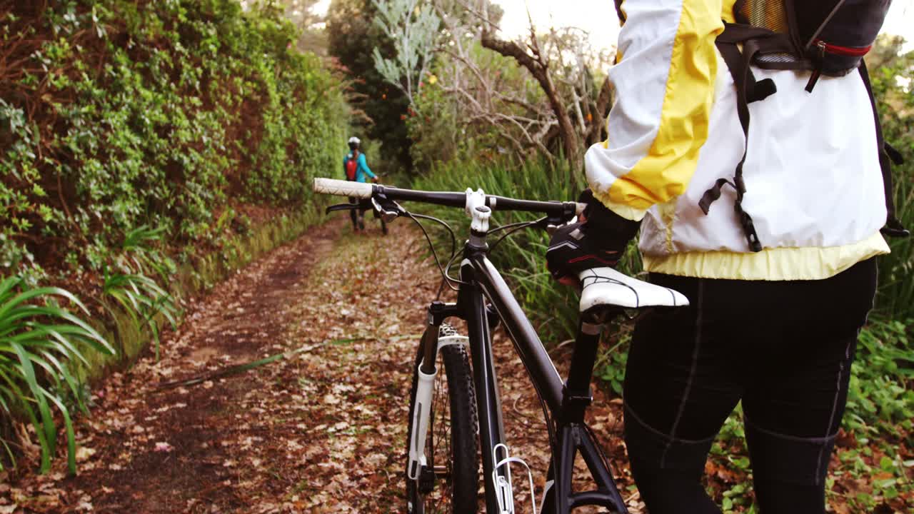 산악 자전거를 타는 부부가 자전거로 숲길을  ⁇ 고 있다