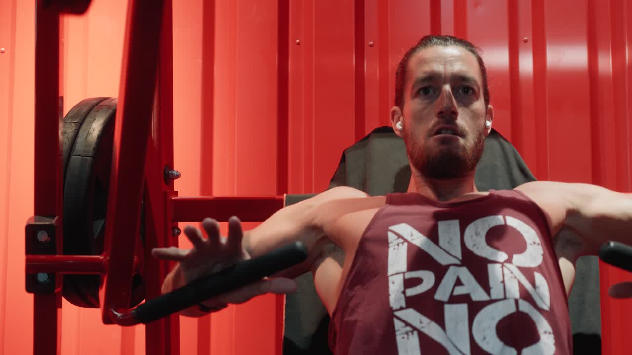 Primer plano de un culturista empezando a hacer repeticiones con un peso elevado en el press de banca