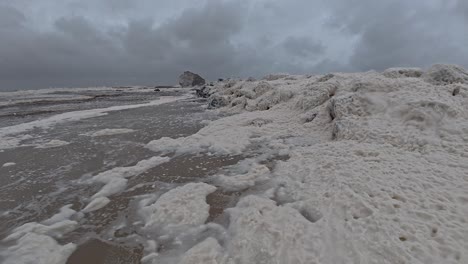 sea foam with wind blowing on cloudy day. cyclone alfred at currumbin beach in gold coast, queensland. static shot