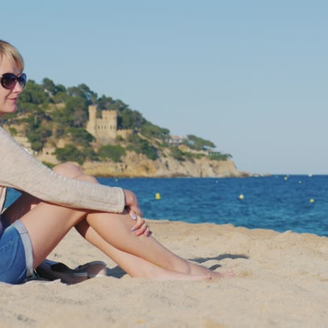 a young tourist sits on the beach by the sea looking into the distance