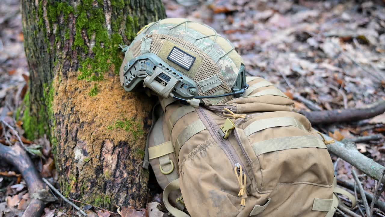 War in Ukraine: Gear of a foreign volunteer soldier during a pause in a tactical training drill. A helmet with a US flag patch and a backpack lie ready in a forest