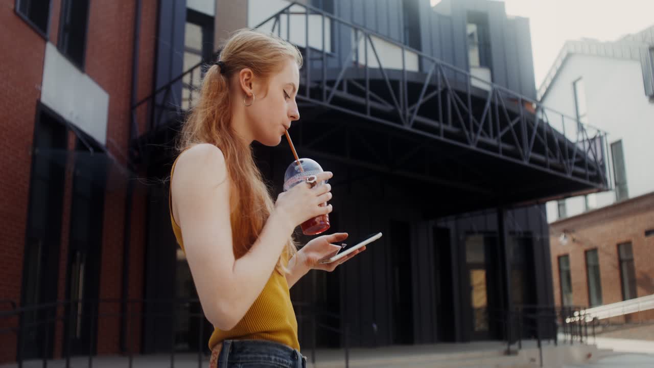 mujer joven con bebida y teléfono al aire libre