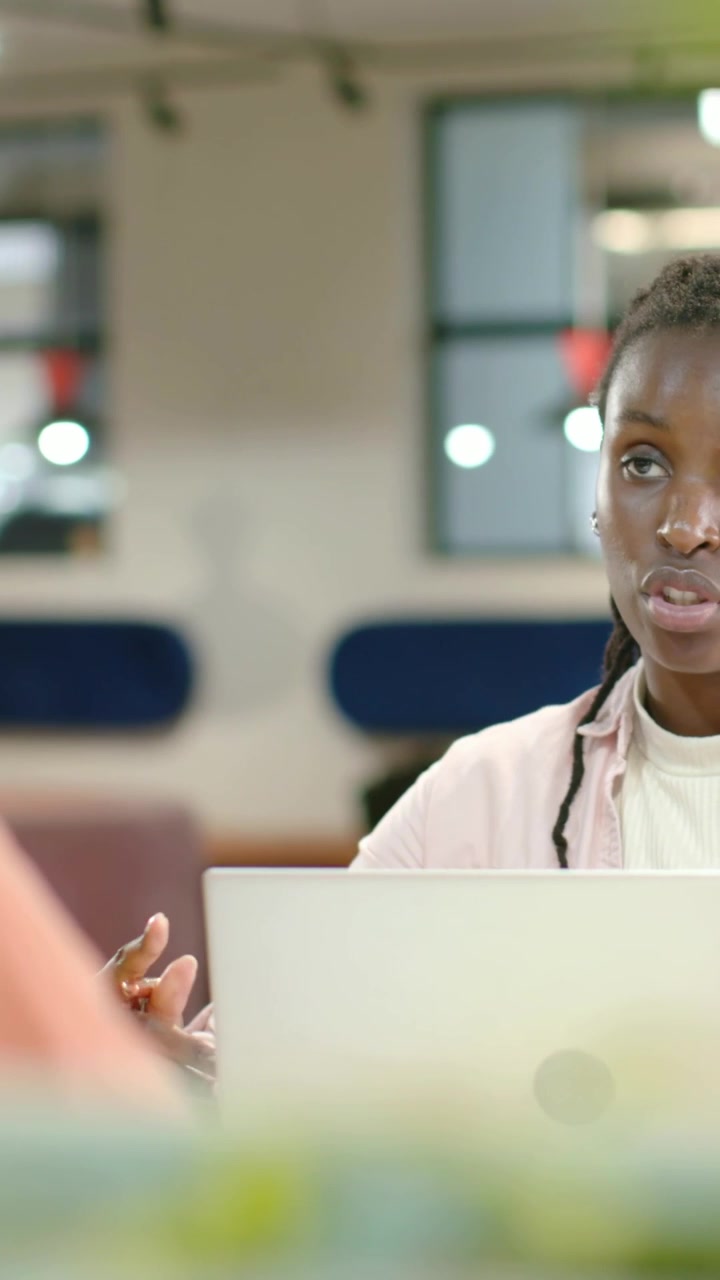 Vertical video: Handing cup nudging woman in pink shifting gaze as typing on laptop at office table