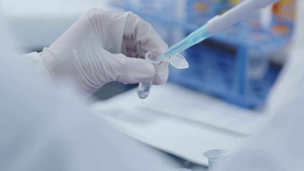 Scientist transferring Solution Samples into Test Tubes flasks with Suction Pipette for cell culture assay, doing molecular experiment in cleanroom facility
