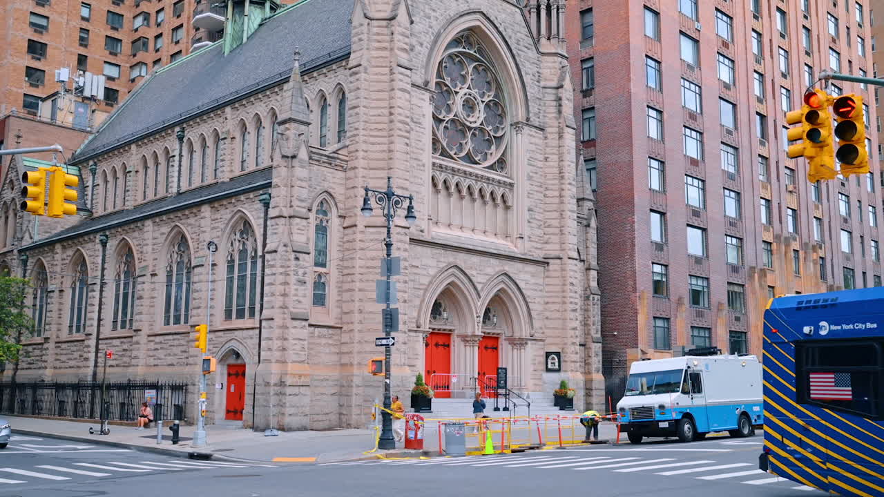 New York, USA, 4 August 2025: Historic church with red doors in New York City. Gothic stone church with red doors on a busy corner