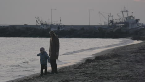 mother with son walking and playing on the beach of aegean sea in the winter nea kallikratia greece