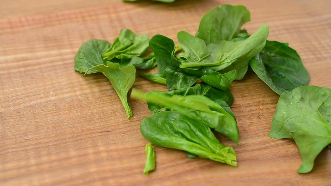 Foglie di spinaci su un tagliere. Riprese in cucina.