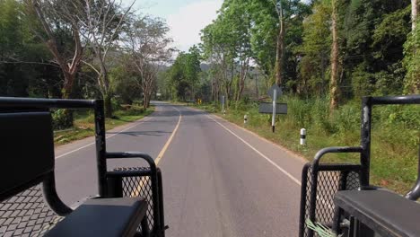 view of asphalt road in khao sok seen from back of a truck