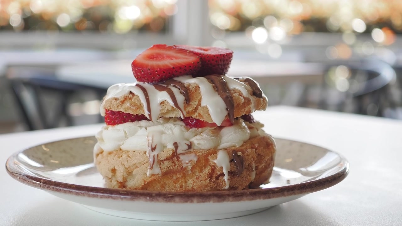 Delizioso dessert di profiteroles con fragole fresche e un filo di cioccolato