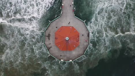 the pacific ocean crashes around the manhattan beach pier in california