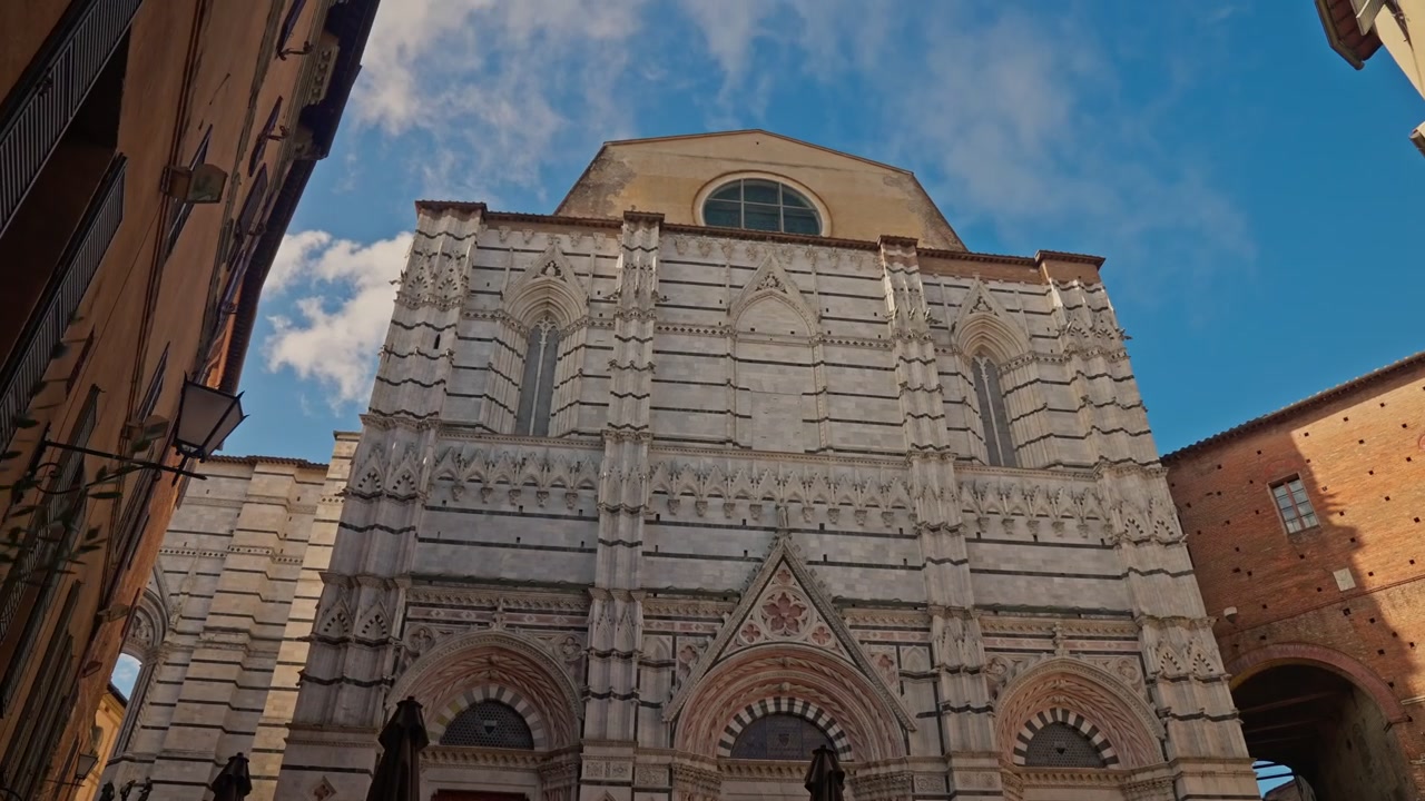La facciata posteriore del Duomo di Siena medievale a Siena, Provincia di Siena, Italia, dalla Piazza S.Giovanni. Panoramica verticale verso l'alto a mano libera.