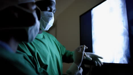 diverse surgeons discussing with x-ray scans in operating theatre at hospital, slow motion