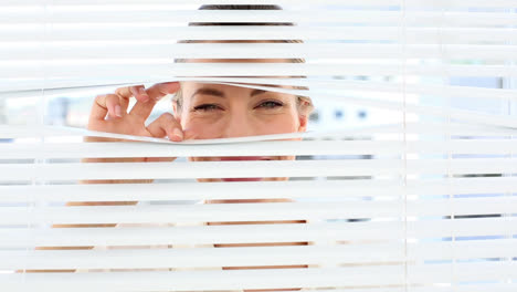 mujer de negocios sorprendida mirando a través de las persianas