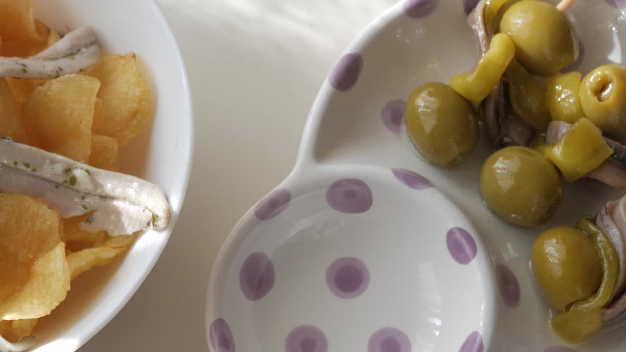 Fresh tapas plate with skewered green olives, anchovies, and a drizzle of olive oil