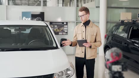 handsome man shoots a video presentation of the car in a car dealership