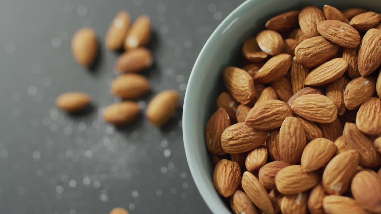 Video of fresh fruit almonds in a bowl on grey background
